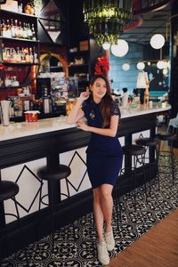 Portrait of young woman standing in restaurant