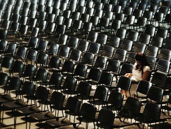 High angle view of woman sitting amidst chairs