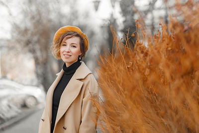 Portrait of smiling young woman standing on land during winter