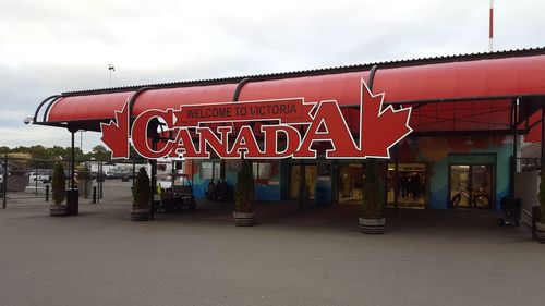 Red road sign on street against sky