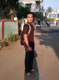 Portrait of young man standing on road in city