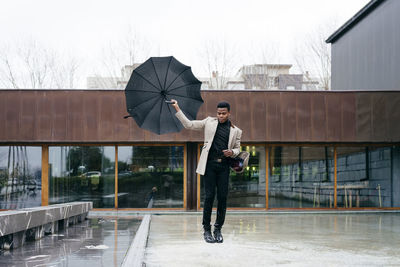 Man with umbrella standing in rain during rainy season