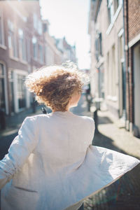 Rear view of woman walking on street against buildings