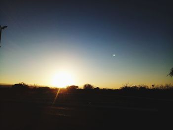 Scenic view of silhouette field against clear sky during sunset