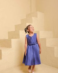 Portrait of young woman standing against wall