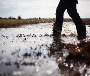 Low section of man standing in puddle