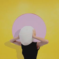 Woman wearing helmet against yellow wall