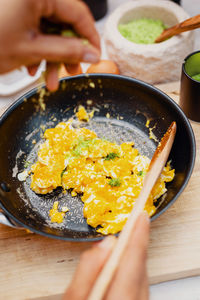 Scrambled eggs in a pan are seasoned with natural herb salt