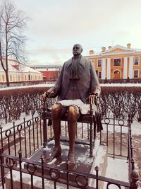 Rear view of man sitting on railing against sky