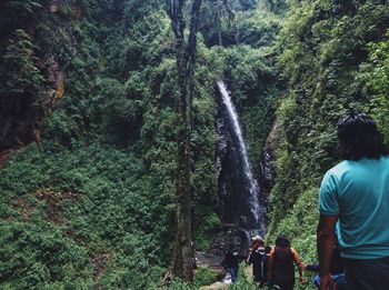 Tourist walking towards waterfall in forest