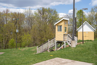 House and trees on field against sky