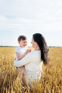 Side view of mother and daughter on field