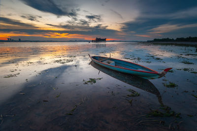 Boat moored on sea against sky during sunset