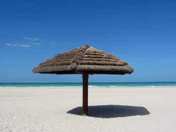 Lifeguard hut on beach against clear blue sky