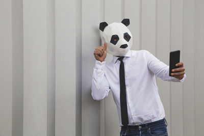 Midsection of man wearing mask standing against white wall