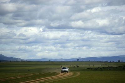 Cars on field against sky