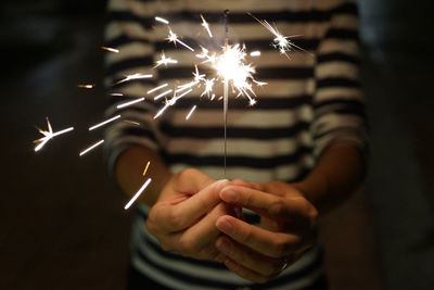 Midsection of man holding sparkler at night