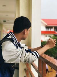 Close-up of boy standing against built structure