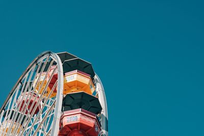 Low angle view of ferris wheel against clear blue sky