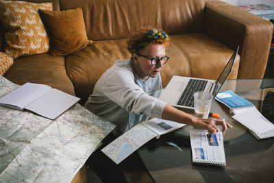 Elderly woman with map and documents planning trip at home