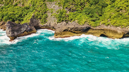 Rocks are washed by white foamy waves. amazing turquoise seascape. nusa penida, indonesia