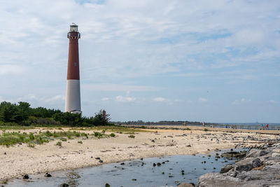 Lighthouse by sea against sky