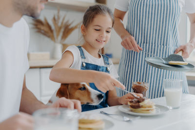 Midsection of parents with daughter having breakfast at home