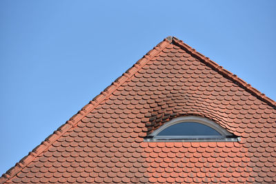 Low angle view of building tiles roof against clear blue sky