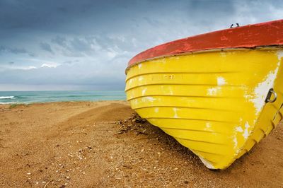 Close-up of yellow umbrella on beach against sky