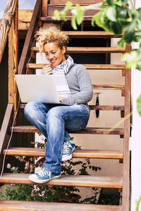 Full length of smiling woman sitting on steps