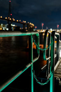 Close-up of illuminated bridge over river in city at night