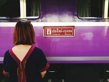 Rear view of woman standing by purple train