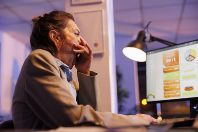 Side view of young woman using mobile phone in office