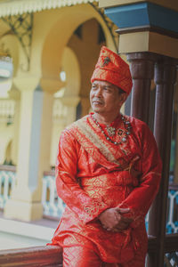 Man in traditional clothing sitting on railing