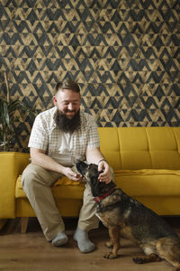 Bearded man stroking dog in living room at home