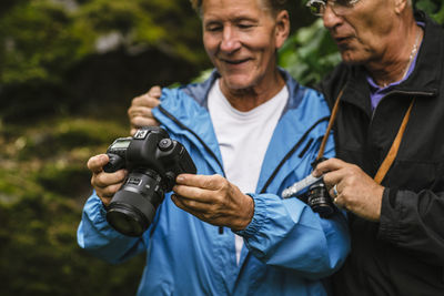 Senior man showing camera to male friend during photography course