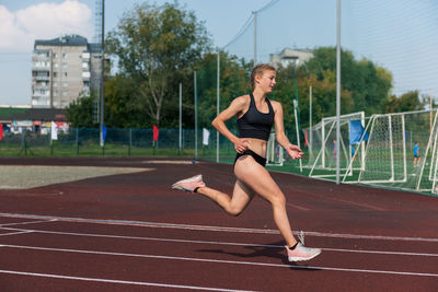 Full length of young woman exercising on road