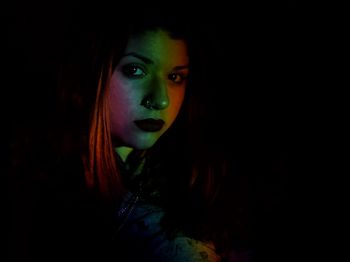 Close-up portrait of young woman in darkroom