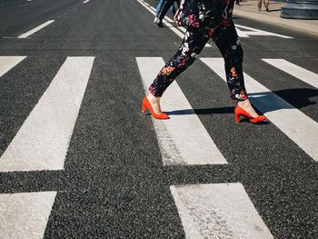 Low section of person crossing sign on road