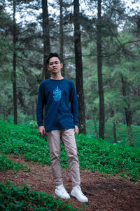 Full length portrait of young man standing at forest