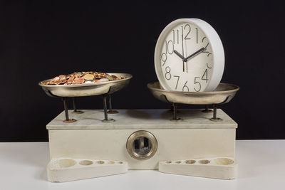 Close-up of clock and coins on machinery against black background