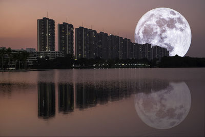 Digital composite image of lake and buildings against sky at night