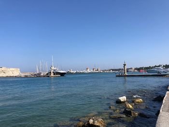 Sailboats in sea against clear blue sky