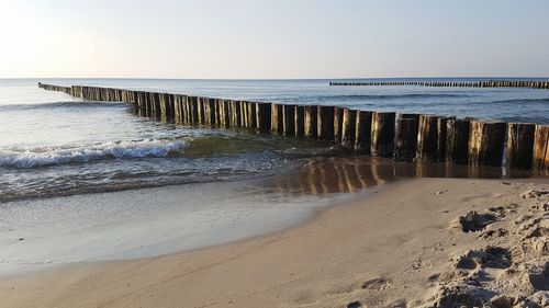 Wooden posts on beach against clear sky