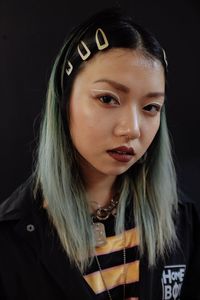 Close-up portrait of young woman against black background