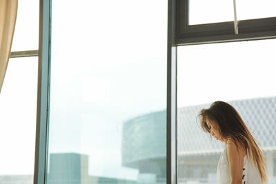 Side view of woman looking through window