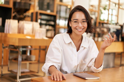 Portrait of young woman using mobile phone in cafe