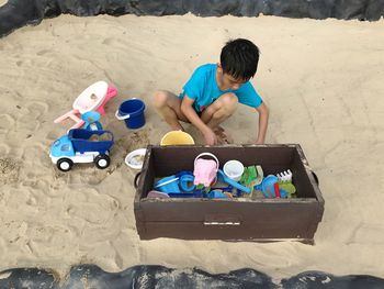 High angle view of boy playing with toy on sand at beach