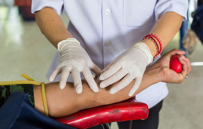 Midsection of nurse taking blood from patient in hospital