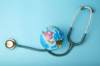 Close-up of globe with stethoscope over blue background